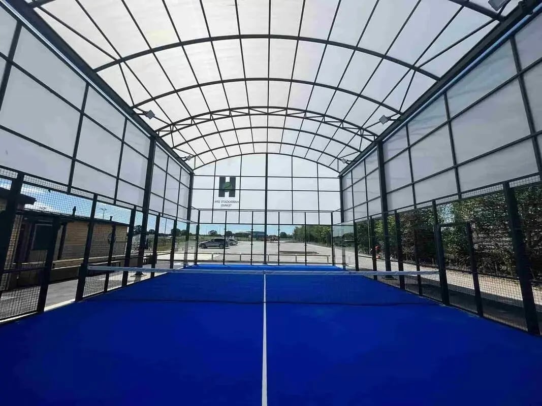 Blue padel court with glass walls and roof playing area at Foundry Courtyard in Glasgow Student Accommodation