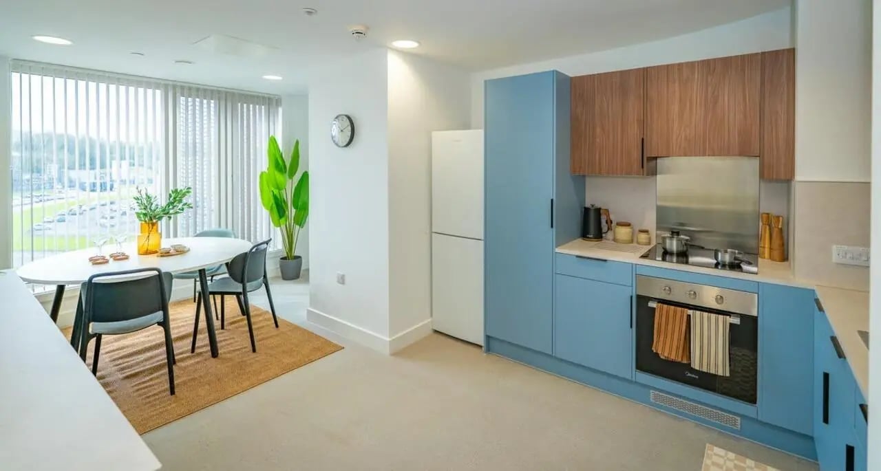 Dining table chairs modern kitchen with blue cabinets kitchen at The Propeller Quarter in Bristol Student Accommodation