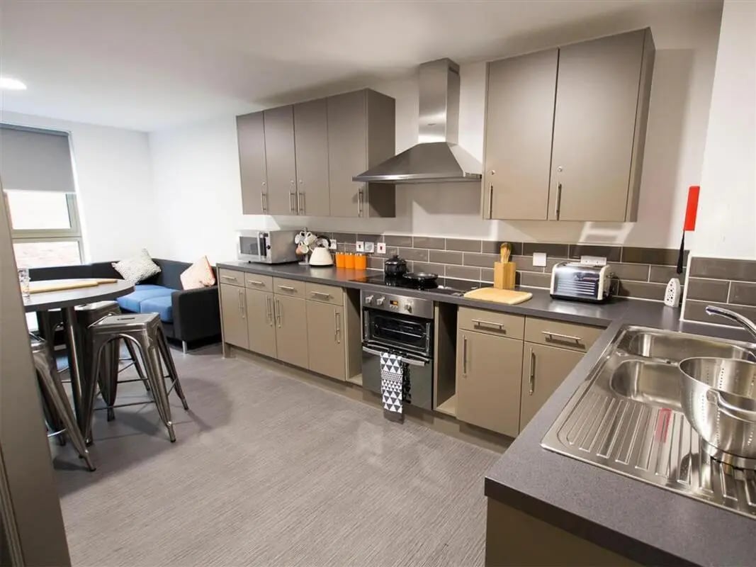 Modern kitchen with grey cabinets stove and sofa kitchen area at Foundry Courtyard in Glasgow Student Accommodation