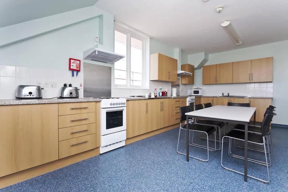 Toasters stove cabinets table chairs kitchen at Pin Hill in Canterbury Student Accommodation