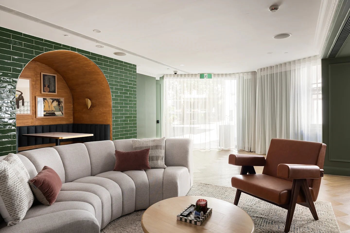 Curved sofa and chair with green tiled walls lounge area at UKO Potts Point in Sydney Student Accommodation