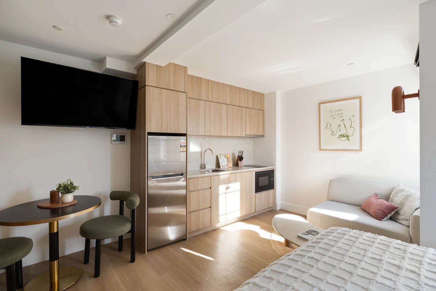 Kitchen area with fridge microwave couch and bed. at UKO Potts Point in Sydney Student Accommodation