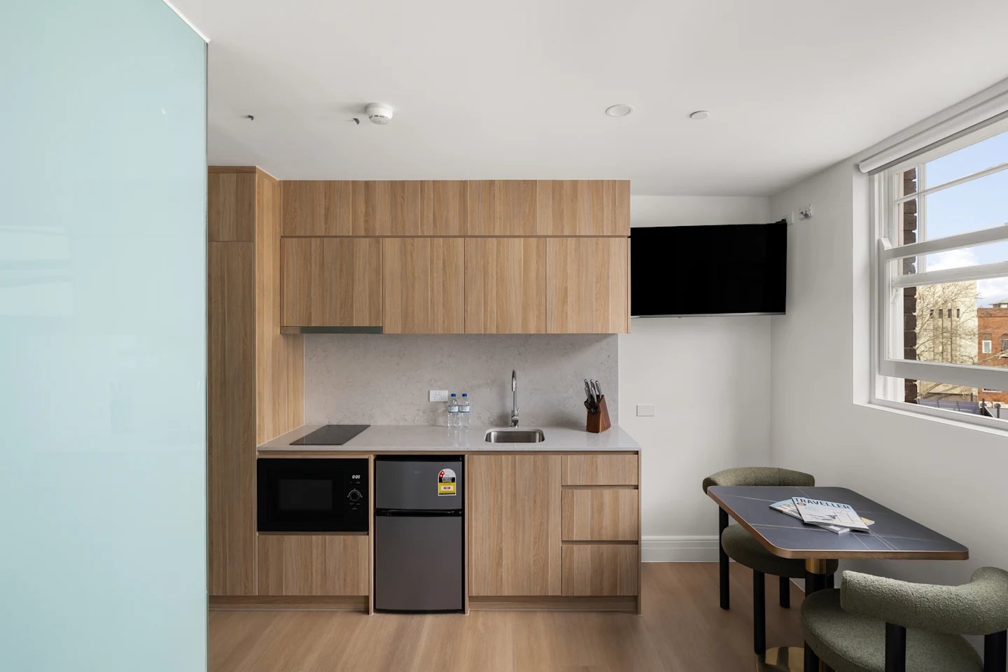 Modern studio kitchen with microwave fridge sink and table dining area at UKO Potts Point in Sydney Student Accommodation