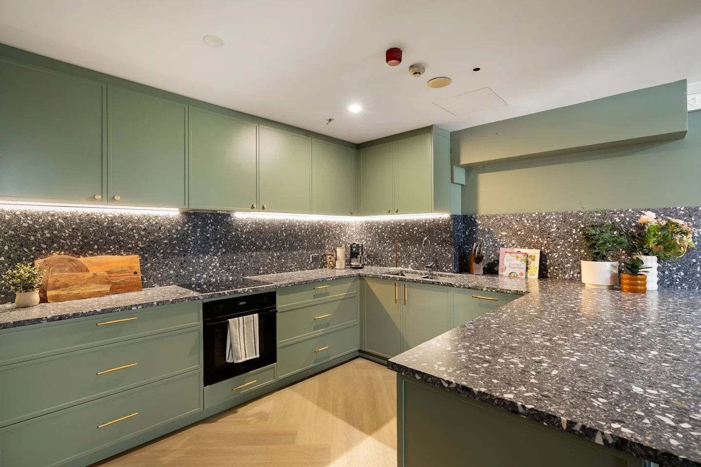 Green cabinets speckled counters oven and sink kitchen at UKO Potts Point in Sydney Student Accommodation