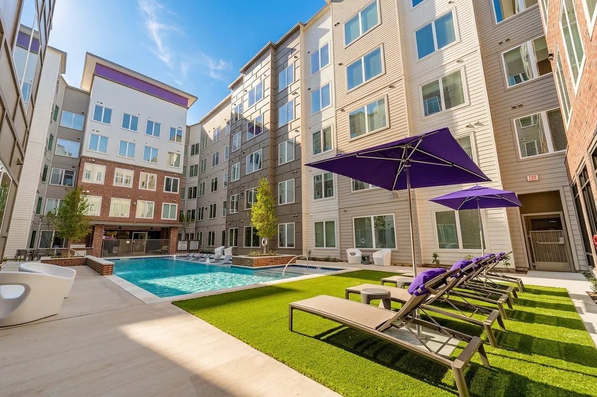 Pool lounge chairs purple umbrellas building exterior at The Edge on Washington Student Housing in Stephenville Student Accommodation