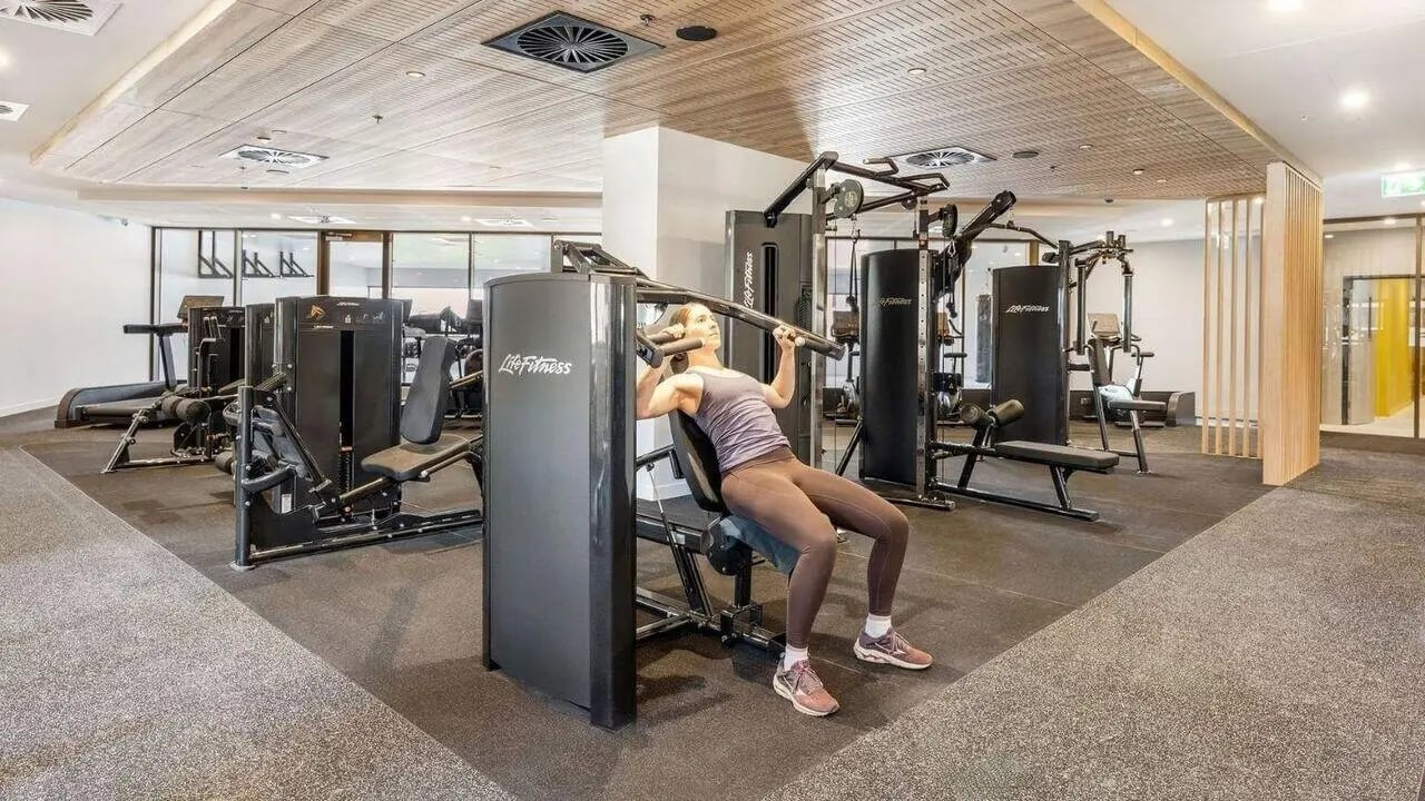Woman on weight machine gym equipment gym at UniLodge Brisbane City in Brisbane Student Accommodation
