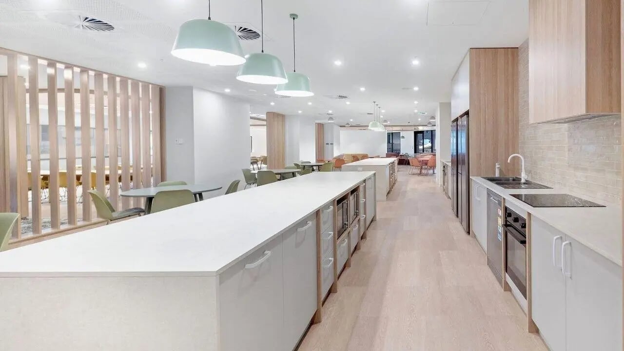 Long kitchen island with microwaves and dining area kitchen at UniLodge Brisbane City in Brisbane Student Accommodation
