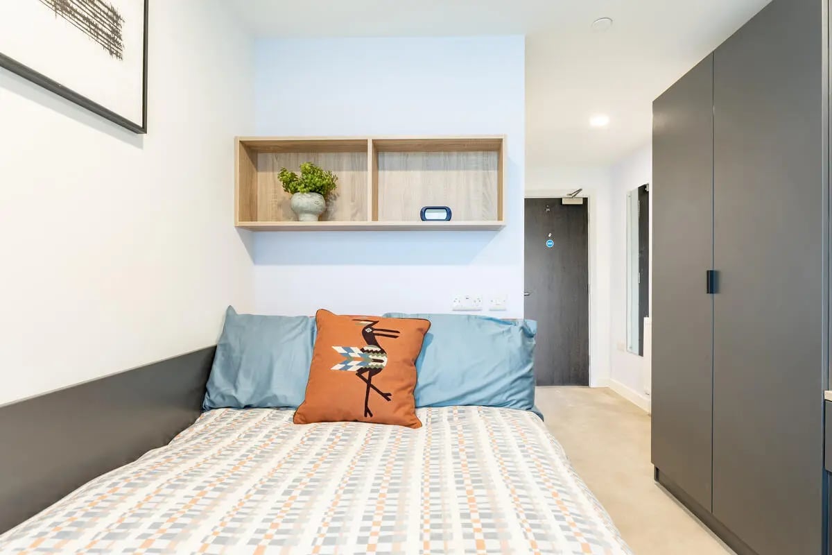 Bed with patterned duvet blue pillows bird pillow bedroom at Croft Court in Bristol Student Accommodation
