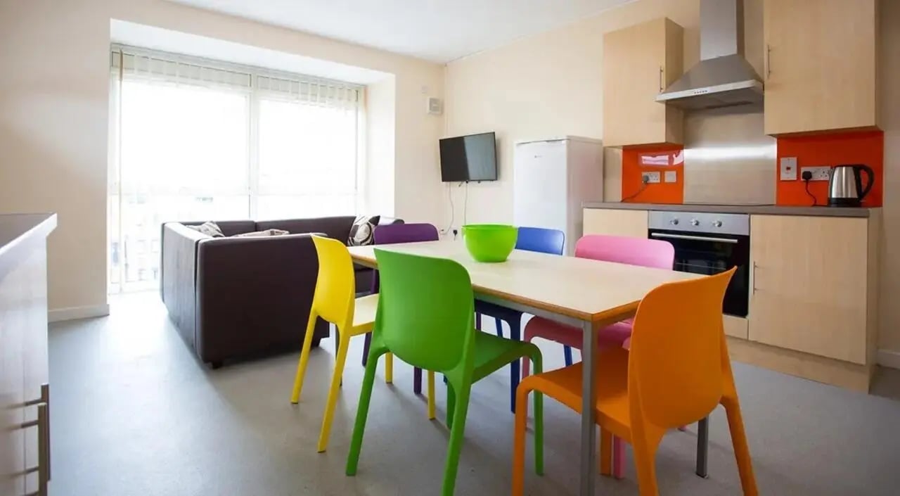 Dining area with colorful chairs kitchen and living room at Brayford Quay in Lincoln Student Accommodation