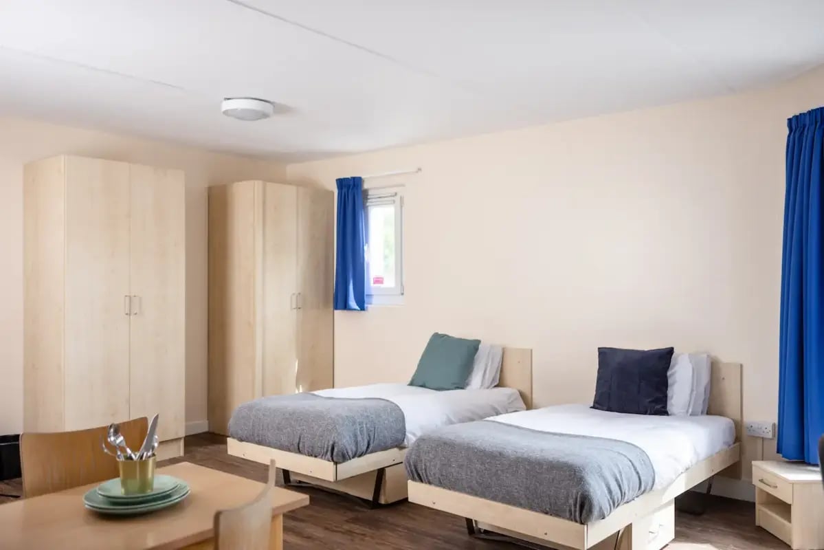Two beds wardrobes table and chairs bedroom at Mcmillan student Village in Greenwich Student Accommodation