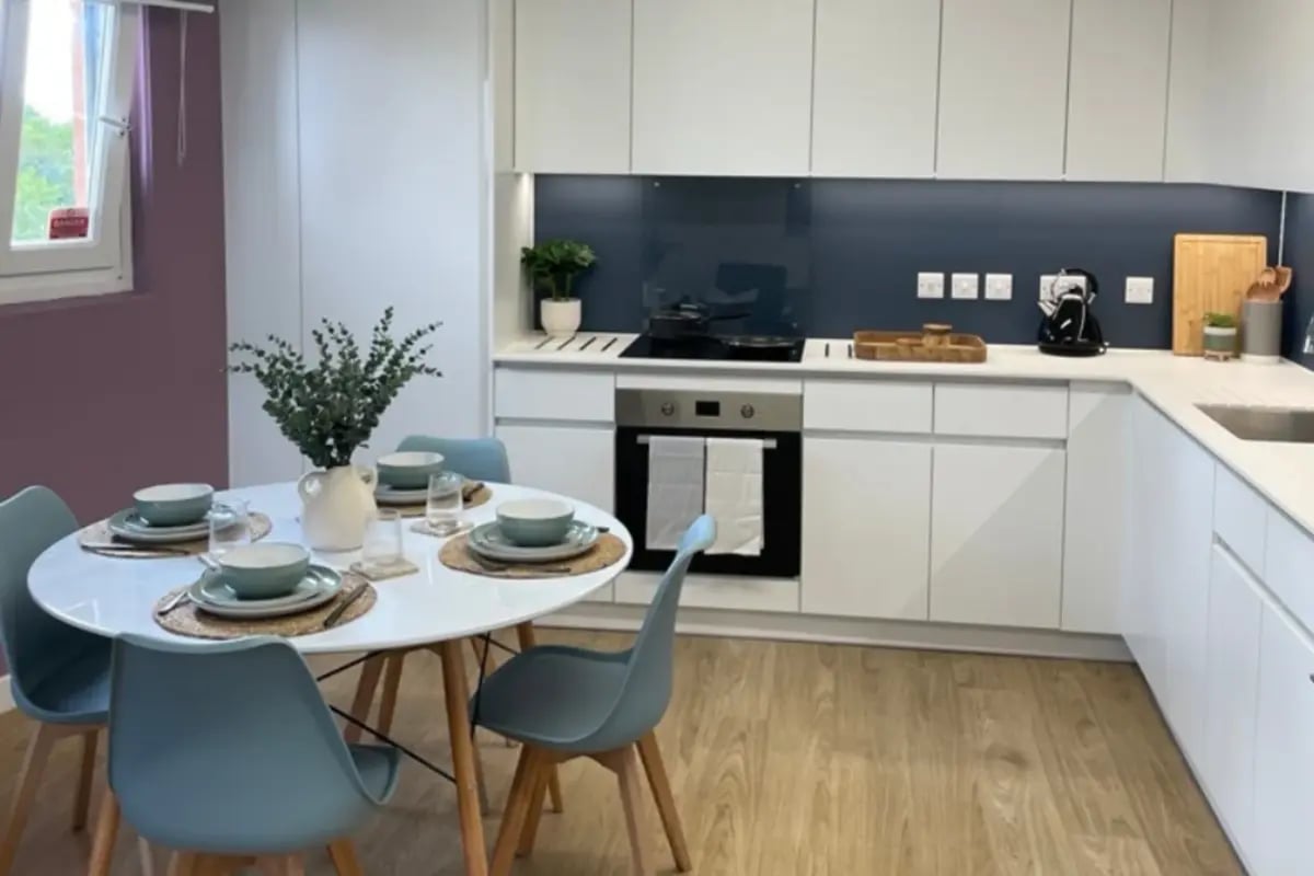 Dining table with place settings and kitchen area kitchen at Mcmillan student Village in Greenwich Student Accommodation