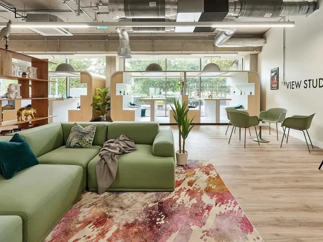 Green couch patterned rug chairs tables study area living room at View Studios in London Student Accommodation