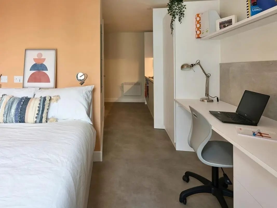 Bed with pillows desk with laptop study area at View Studios in London Student Accommodation