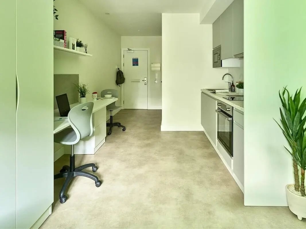Desk laptop chairs small kitchen living room at View Studios in London Student Accommodation
