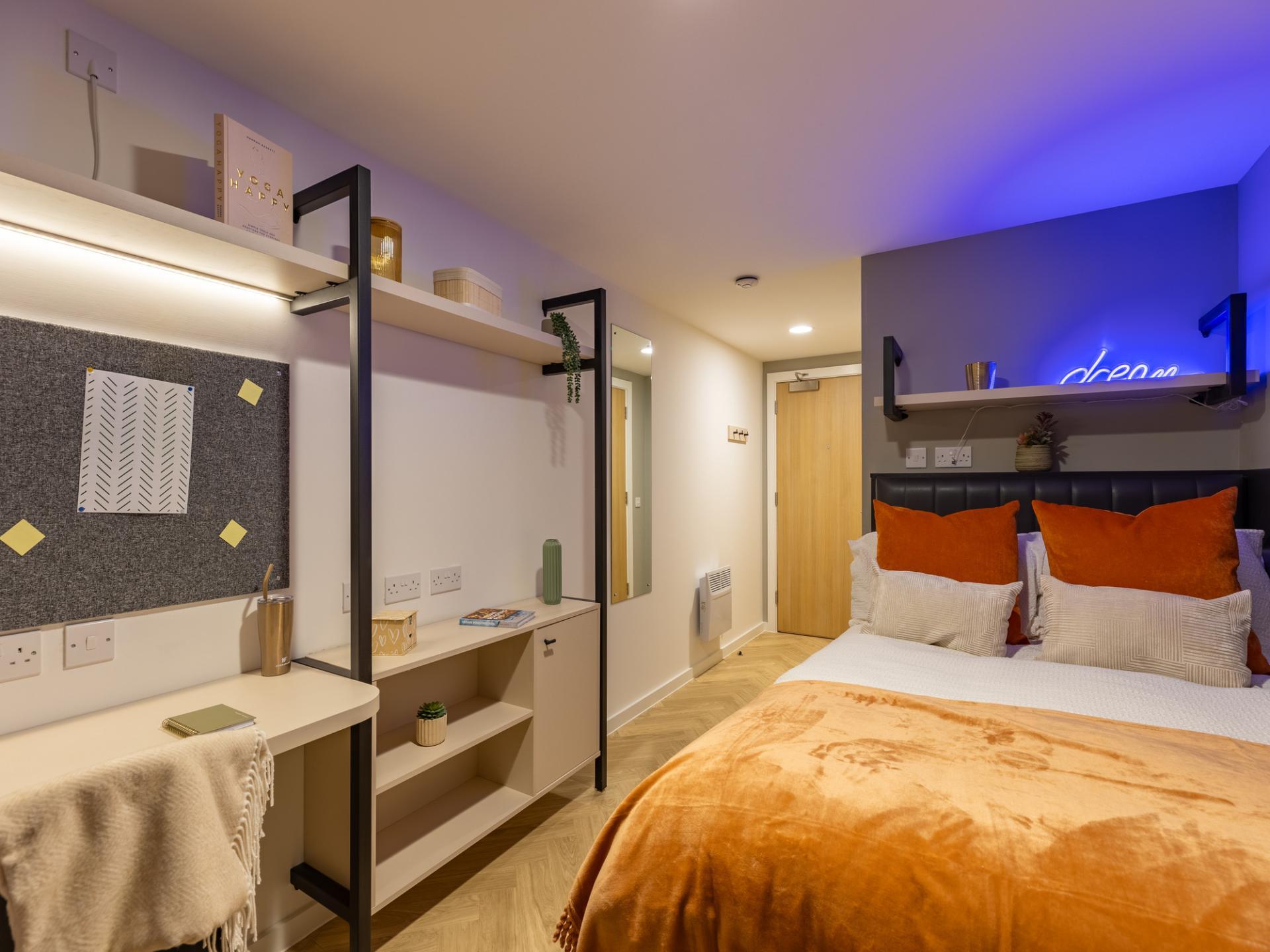 Desk shelf and bed with orange throws bedroom at Arcadian in Nottingham Student Accommodation