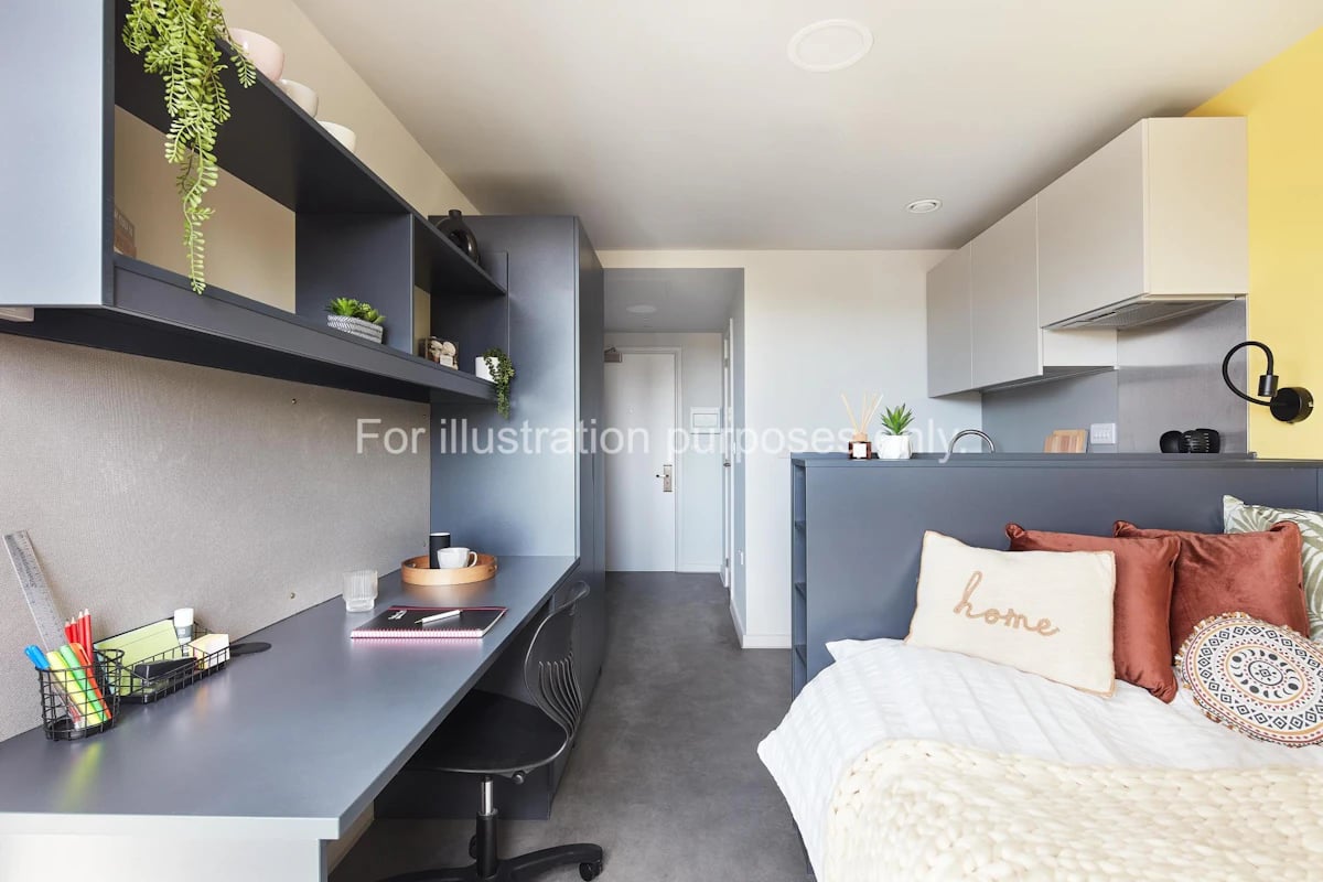 Desk bed shelving and kitchen are visible bedroom at Ravilious House in Brighton Student Accommodation