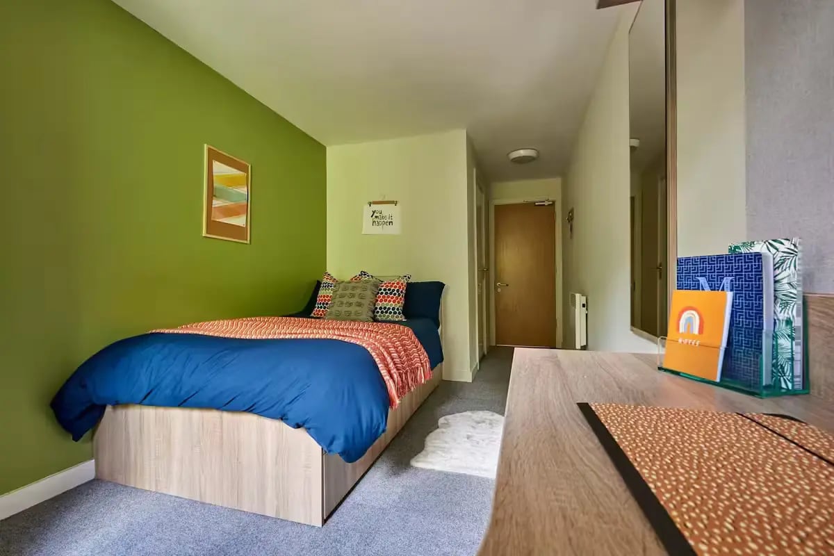 Bed with blue duvet and orange throw artwork bedroom at Selly Oak Court in Birmingham Student Accommodation