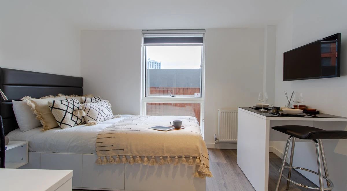 Bed with patterned pillows and desk area bedroom at Miura in Nottingham Student Accommodation