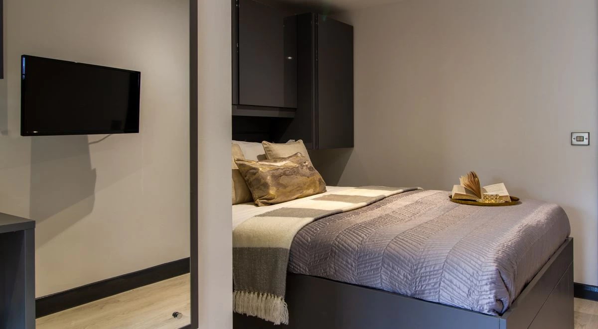Bed with pillows TV and cabinets bedroom at The Residence in Coventry Student Accommodation
