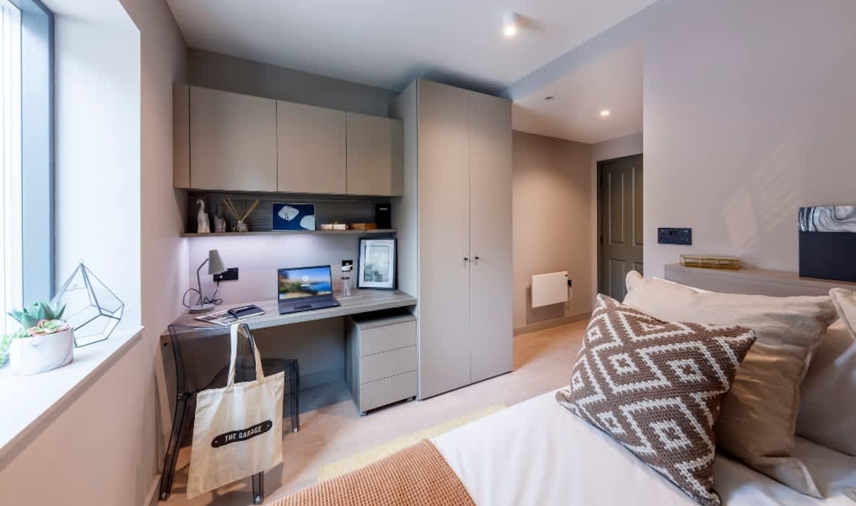 Desk laptop plants wardrobe and bed Bedroom at The Garage Egham in Egham Student Accommodation