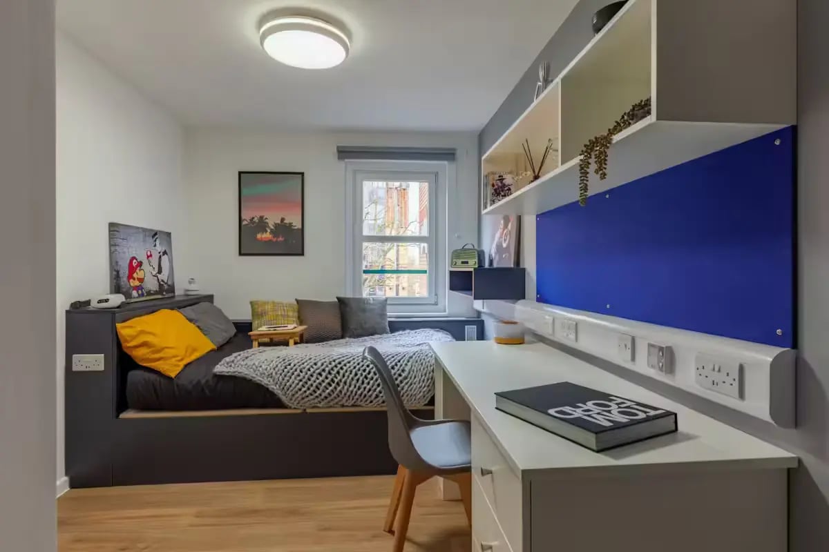 Bed with yellow cushion and desk area Bedroom at The Bridge Guildford in Guildford Student Accommodation