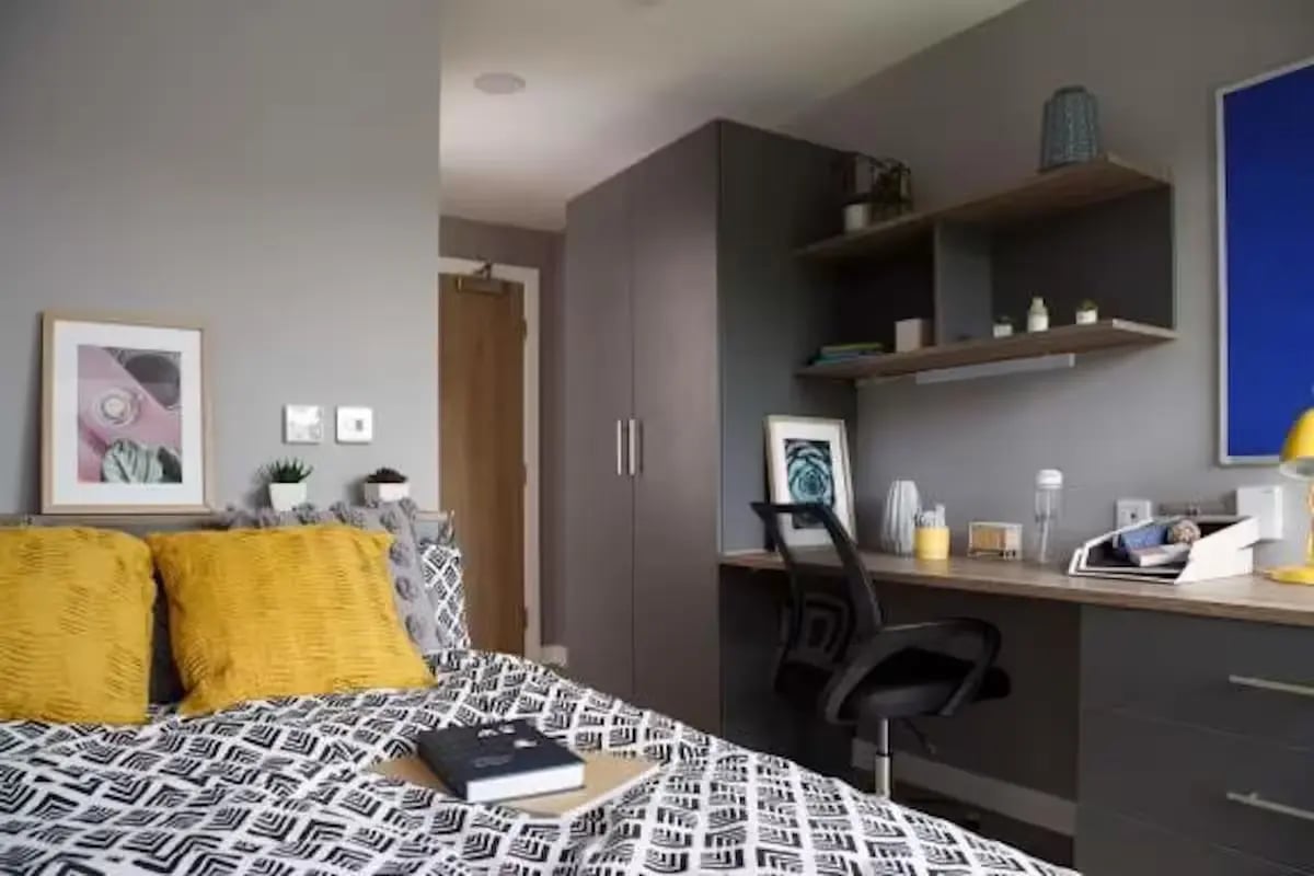 Bed with yellow pillows and desk study area bedroom at Luneside in Lancaster Student Accommodation
