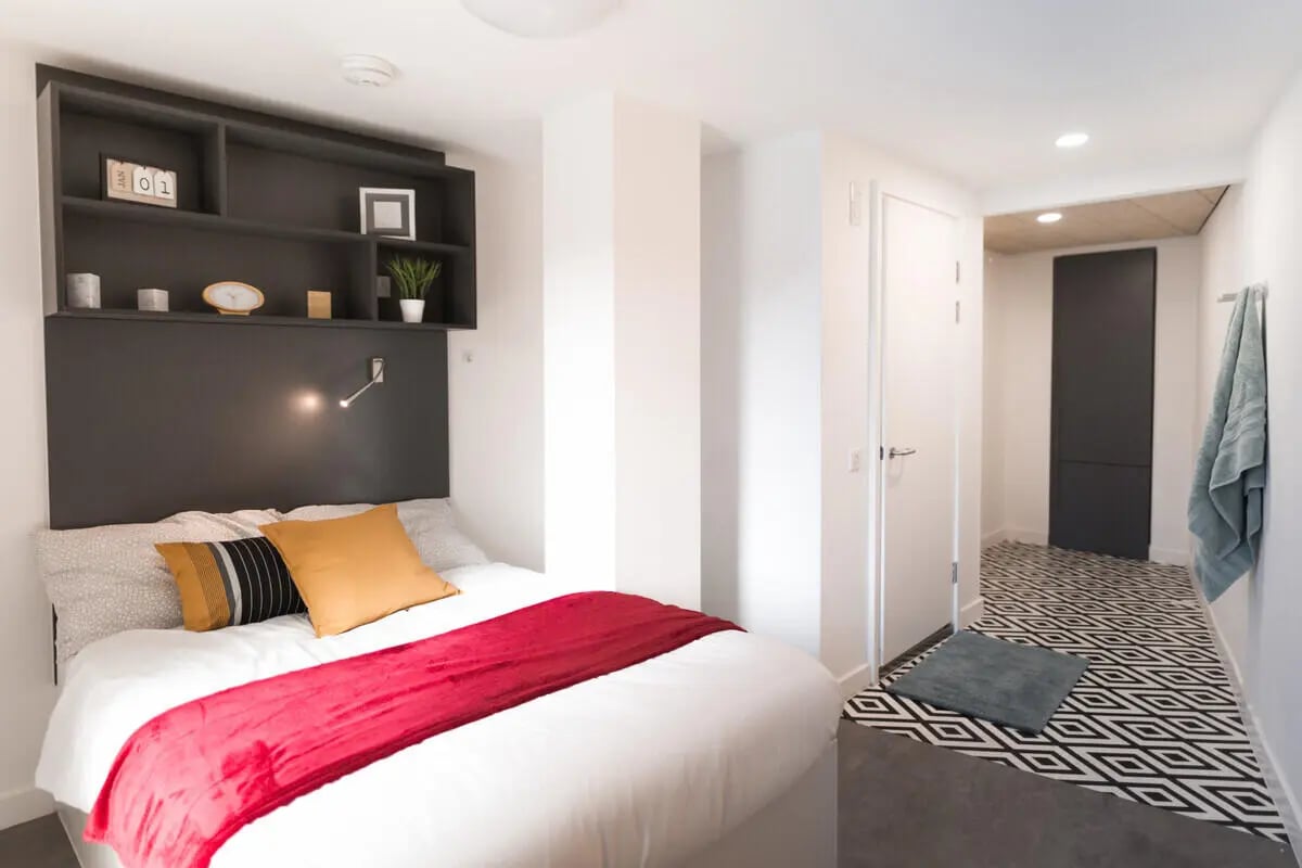 Bed with red blanket and shelves bedroom at AXO Paradise Student Village in Coventry Student Accommodation