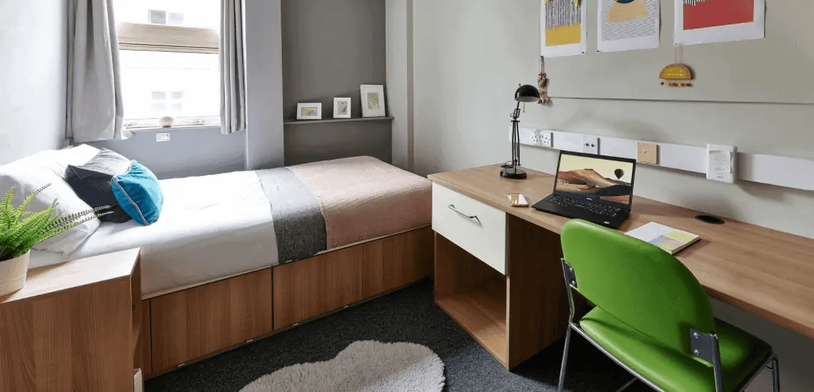 Bed desk laptop and green chair bedroom at Northernhay House in Exeter Student Accommodation