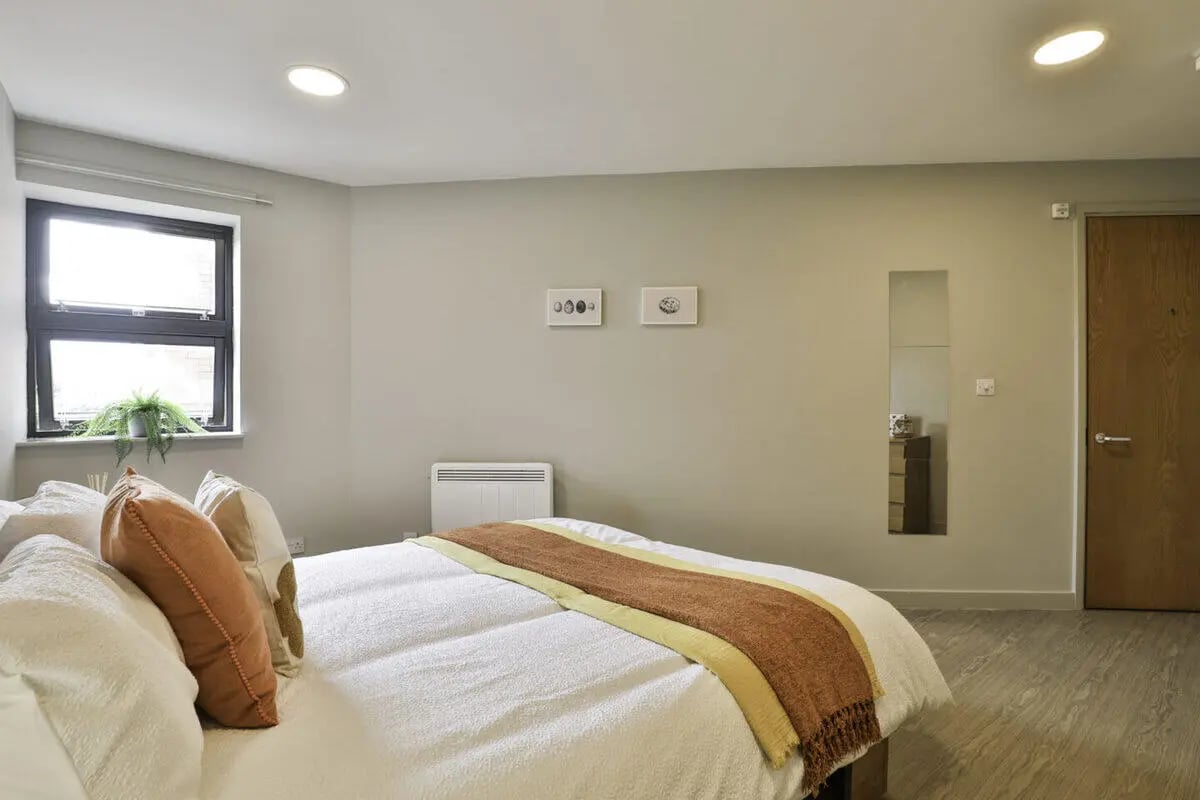 Bed with cushions heater window dresser mirror bedroom at Ladybarn House in Manchester Student Accommodation