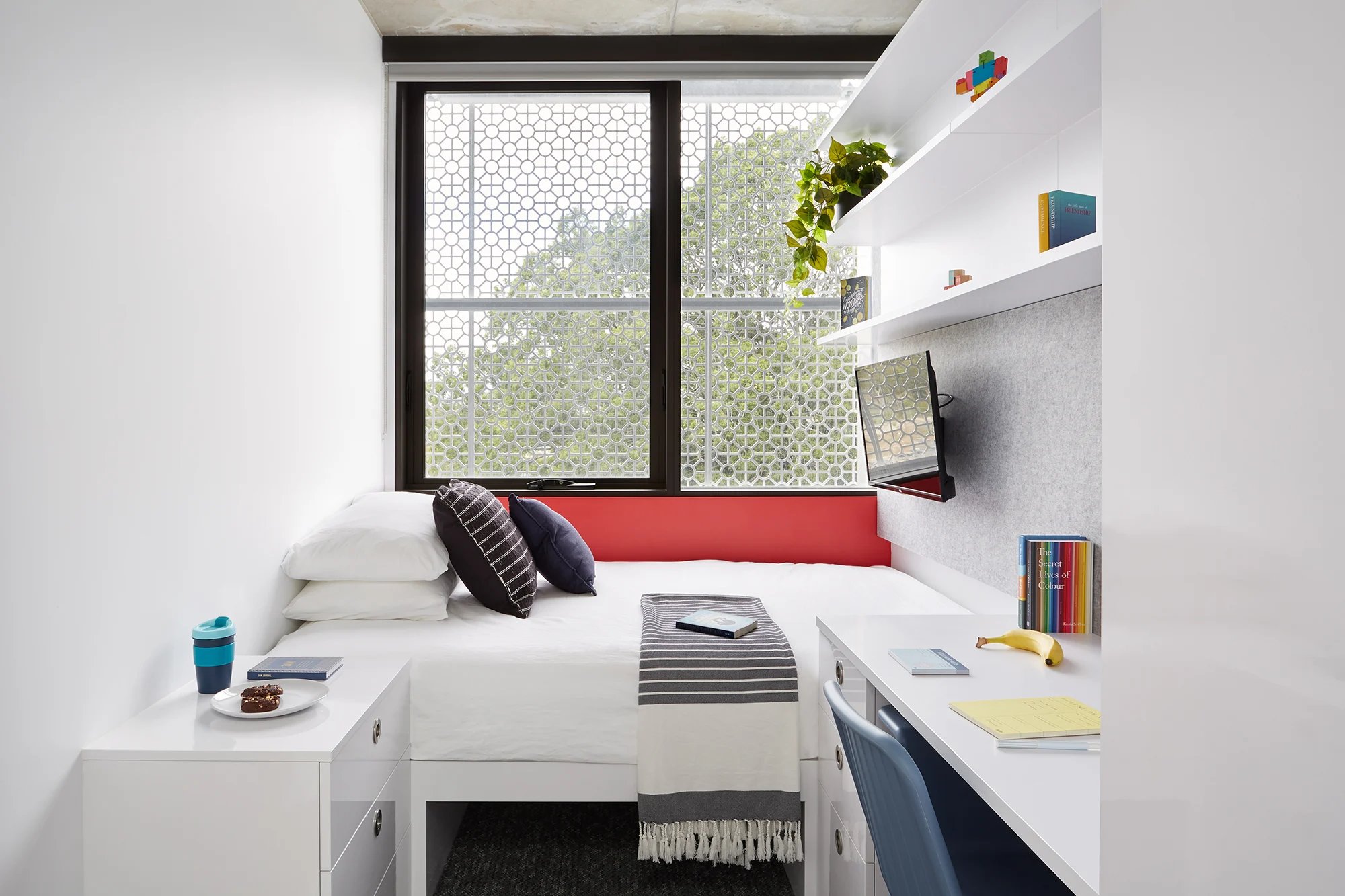 Bed desk and shelf with books and plant bedroom at Scape Toowong in Brisbane Student Accommodation