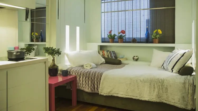 Bed with pillows and kitchen area bedroom at The Stay Club - Camden in London Student Accommodation