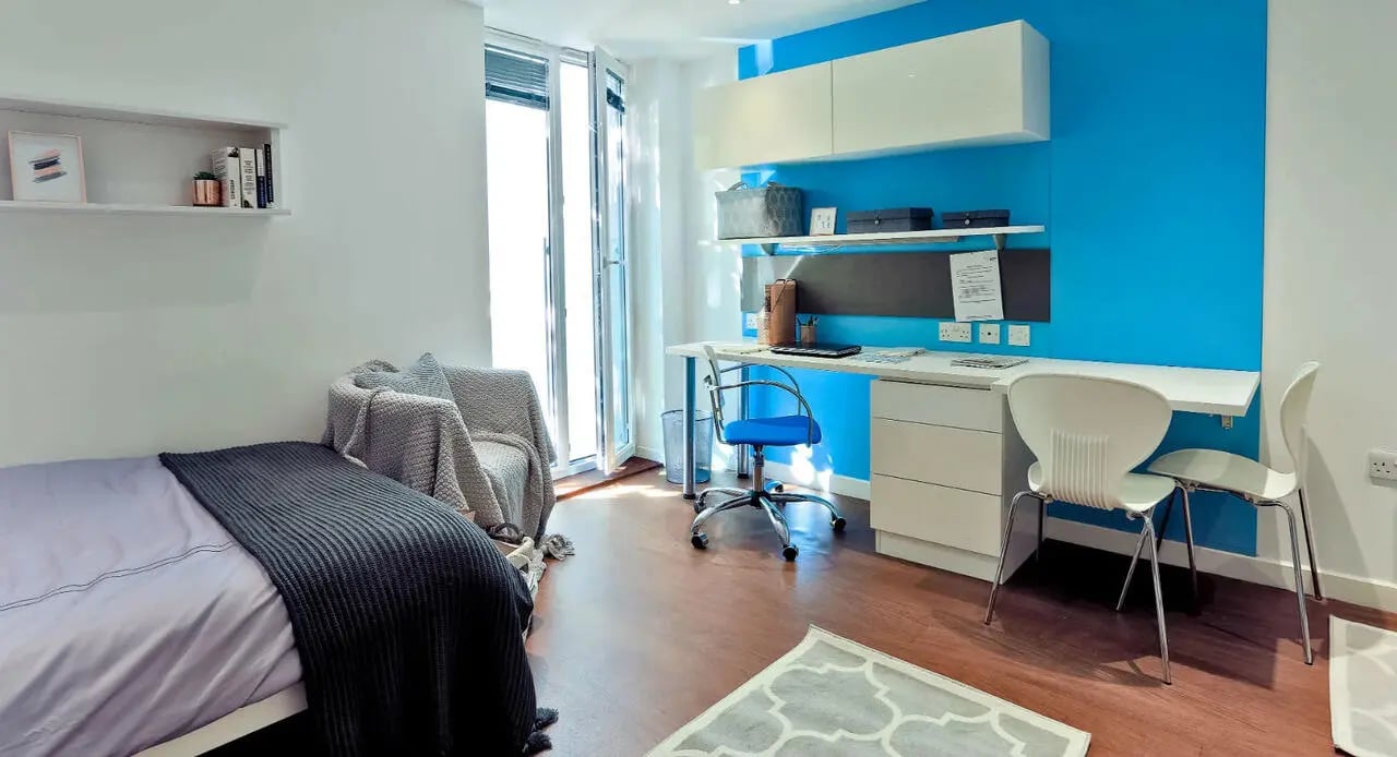 Bed armchair desk and chairs bedroom at Griffon Studios in London Student Accommodation