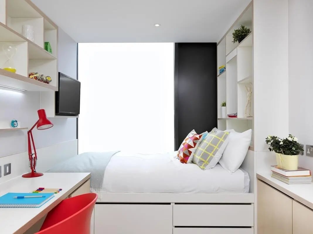 Bed with pillows desk lamp and shelves bedroom at Student Castle Cambridge in Cambridge Student Accommodation