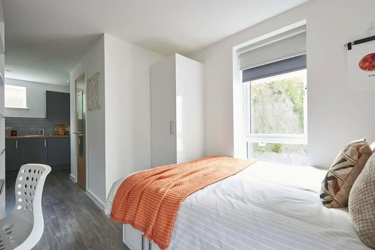 Bed wardrobe white chair small kitchen bedroom at The Reservoir in Plymouth Student Accommodation
