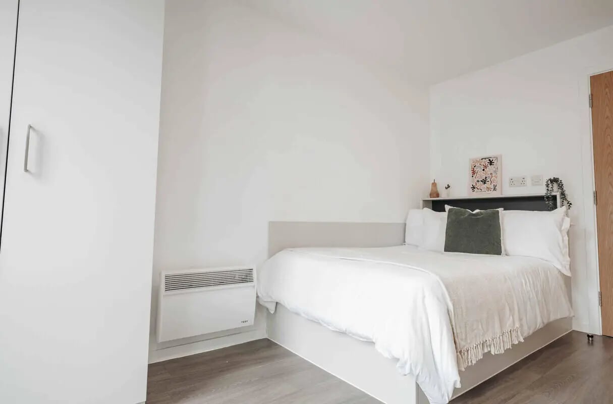 Bed with white linens green pillow artwork bedroom at Alma Court in Canterbury Student Accommodation