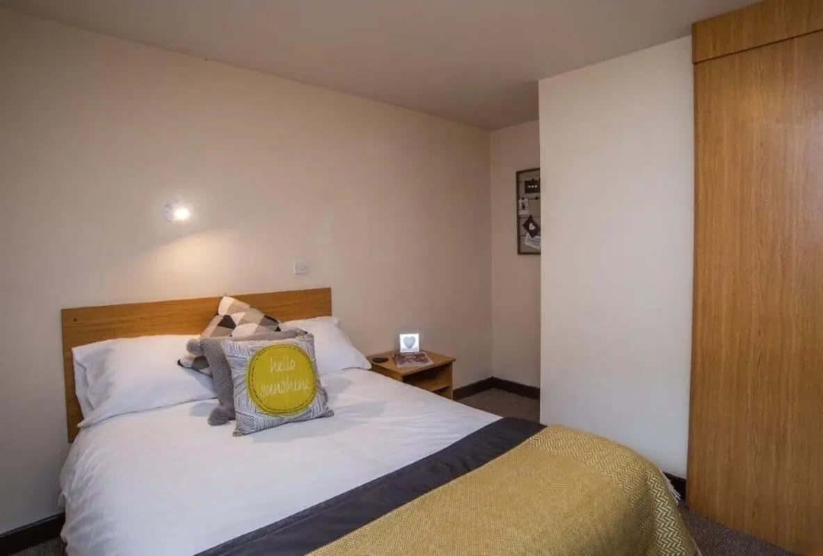 Bed with yellow pillow wardrobe bedroom at Asha House in Loughborough Student Accommodation