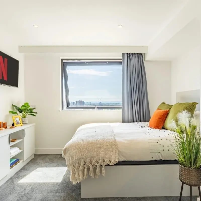 Bed with white bedding and decorative pillows bedroom at True Manchester-Salford in Salford Student Accommodation