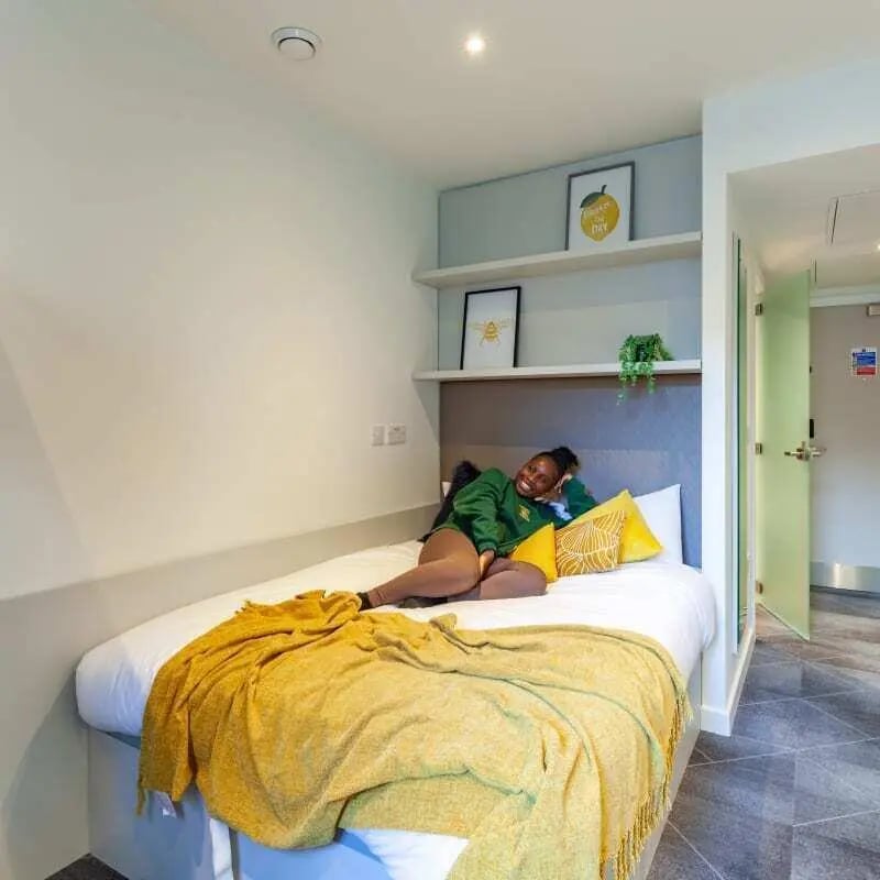 Bed with yellow blanket framed art bedroom at True Birmingham in Birmingham Student Accommodation