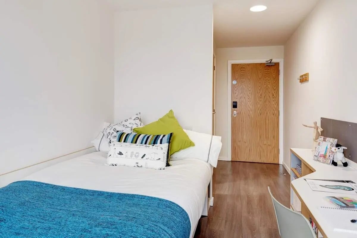 Bed with blue throw and patterned pillows study desk bedroom at Dunaskin Mill in Glasgow Student Accommodation