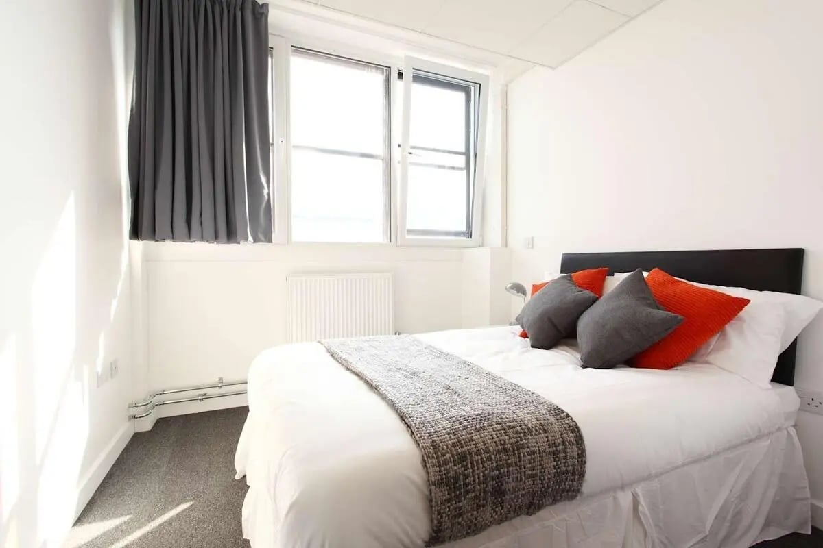 Bed with grey and orange pillows and throw Bedroom at MyPad Paisley in Paisley Student Accommodation