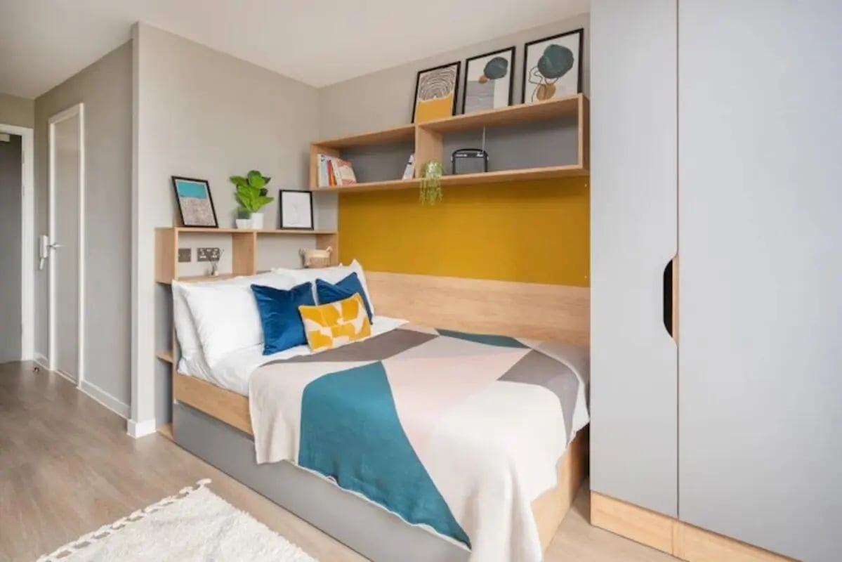 Bed with blue pillows and patterned throw bedroom at Zinc Quarter in Bristol Student Accommodation