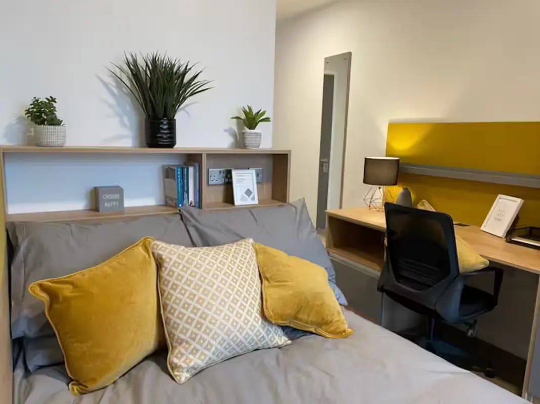 Bed with yellow pillows and a desk Bedroom at Hillfort House in Brighton Student Accommodation