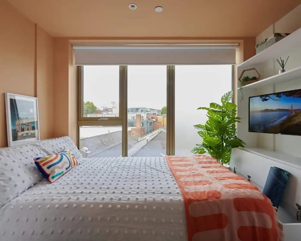 Bed with colorful pillow and TV bedroom. at Host View Studios in London Student Accommodation