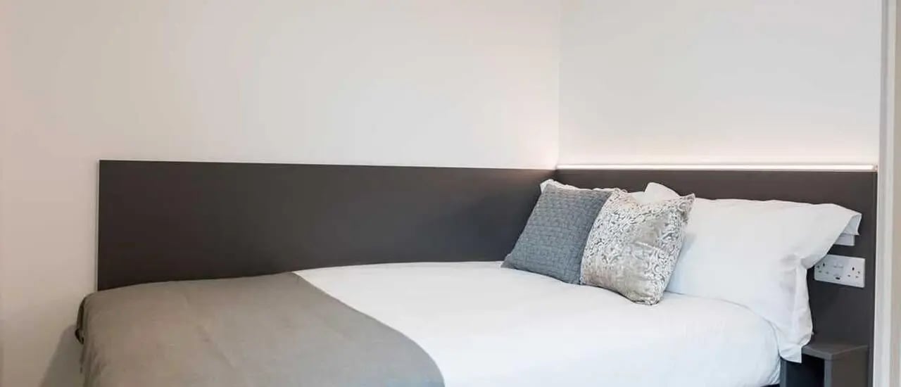 Bed with pillows and grey throw Bedroom at Chapter Highbury II in London Student Accommodation