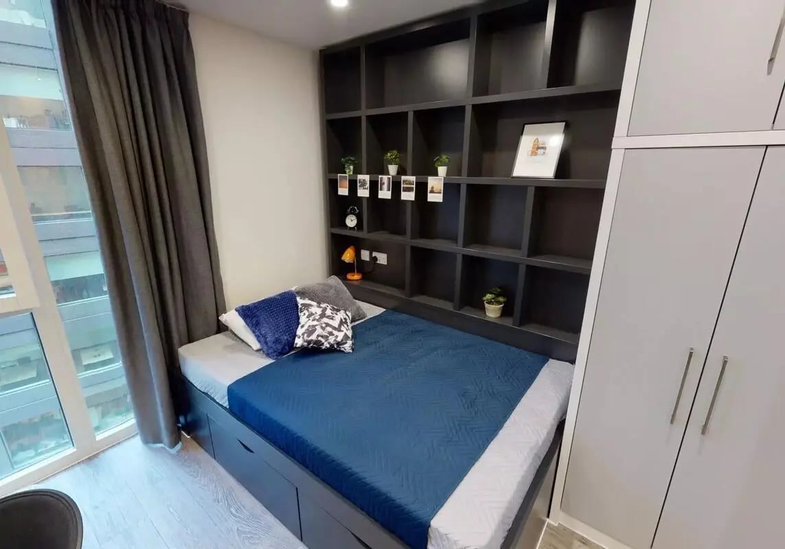Bed with blue covers shelves and wardrobe bedroom at iQ Shoreditch in London Student Accommodation