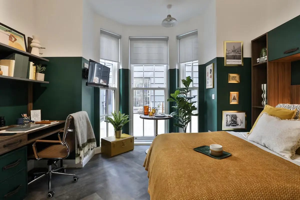 Desk chair bed TV plants and framed art bedroom at James House in Bath Student Accommodation