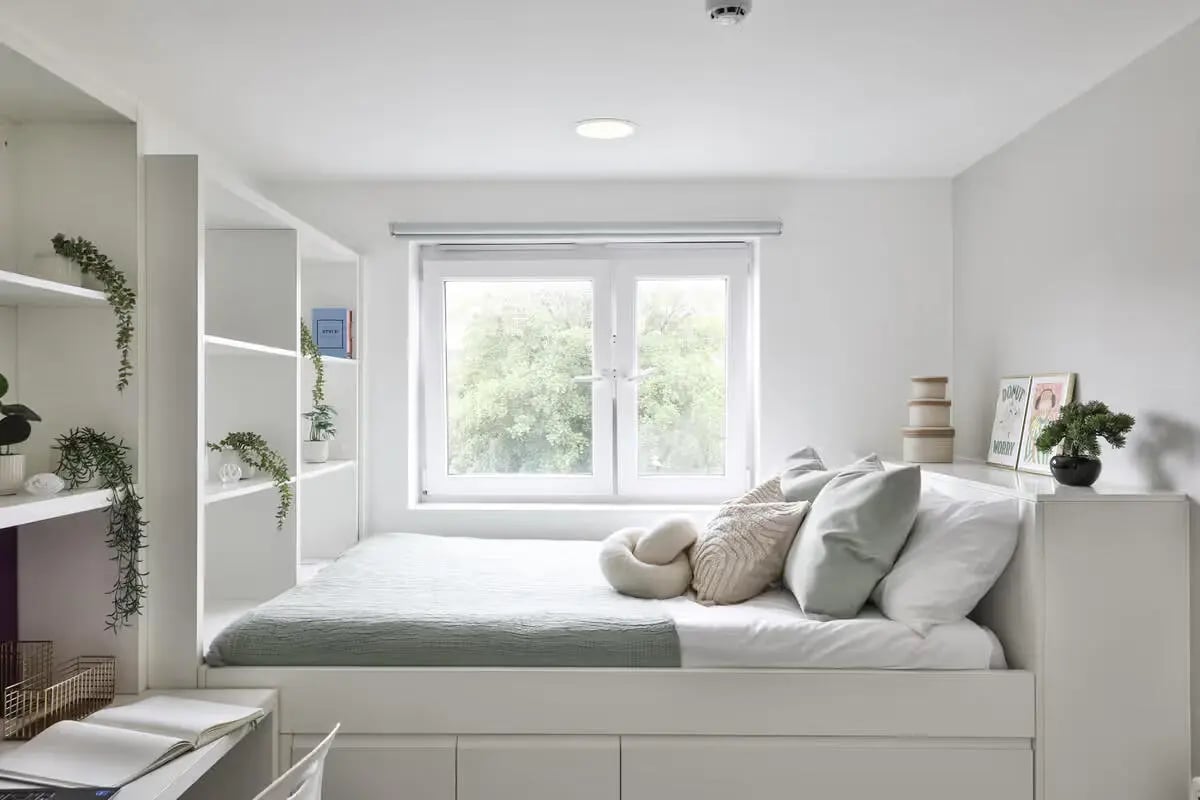 Bed with pillows shelves window and desk Bedroom at James House in Bath Student Accommodation
