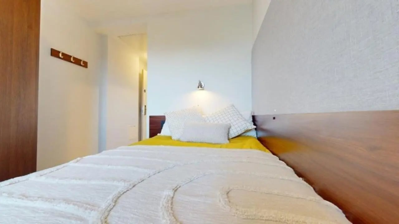 Bed with pillows and yellow throw Bedroom at iQ Highbury in London Student Accommodation