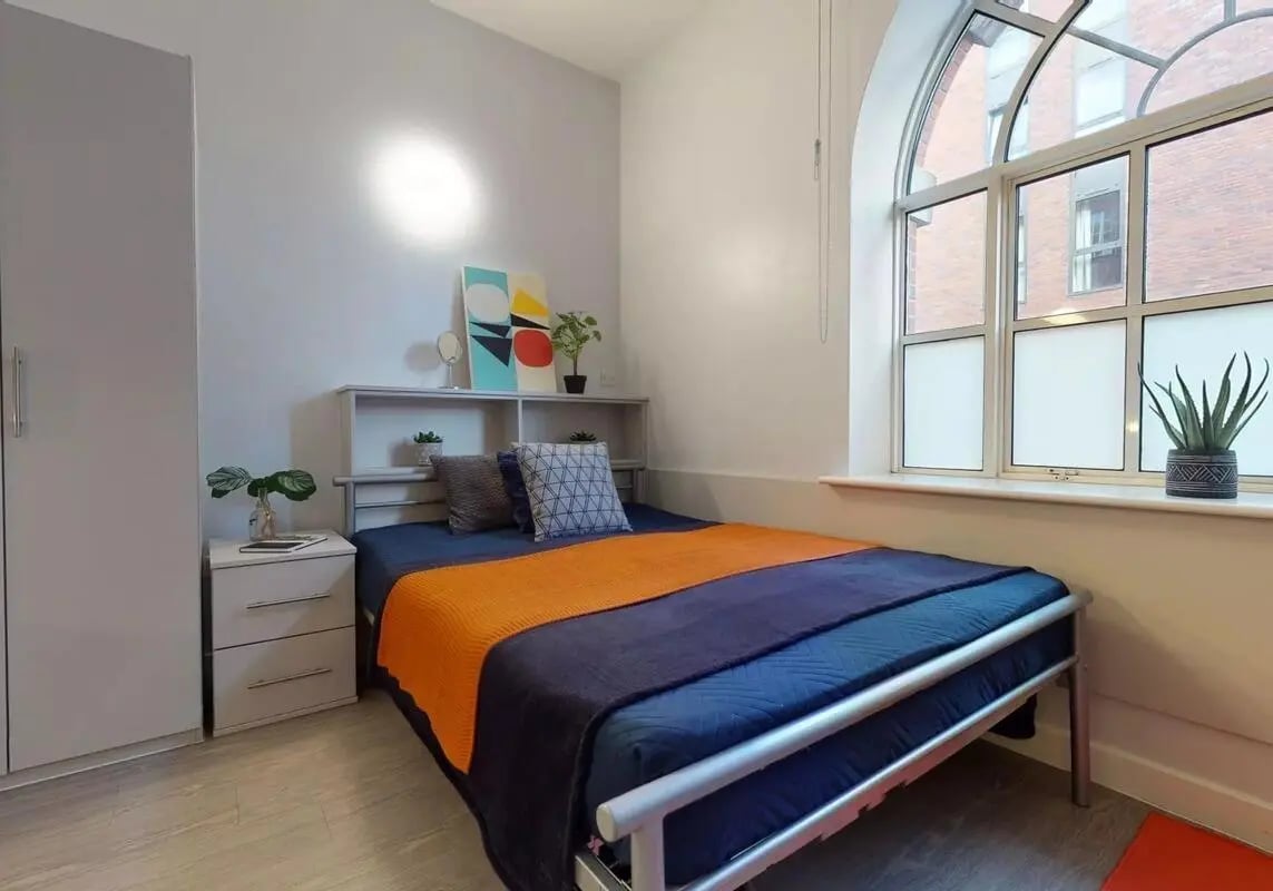 Bed with orange throw and nightstand bedroom at iQ Studios 51 in Birmingham Student Accommodation