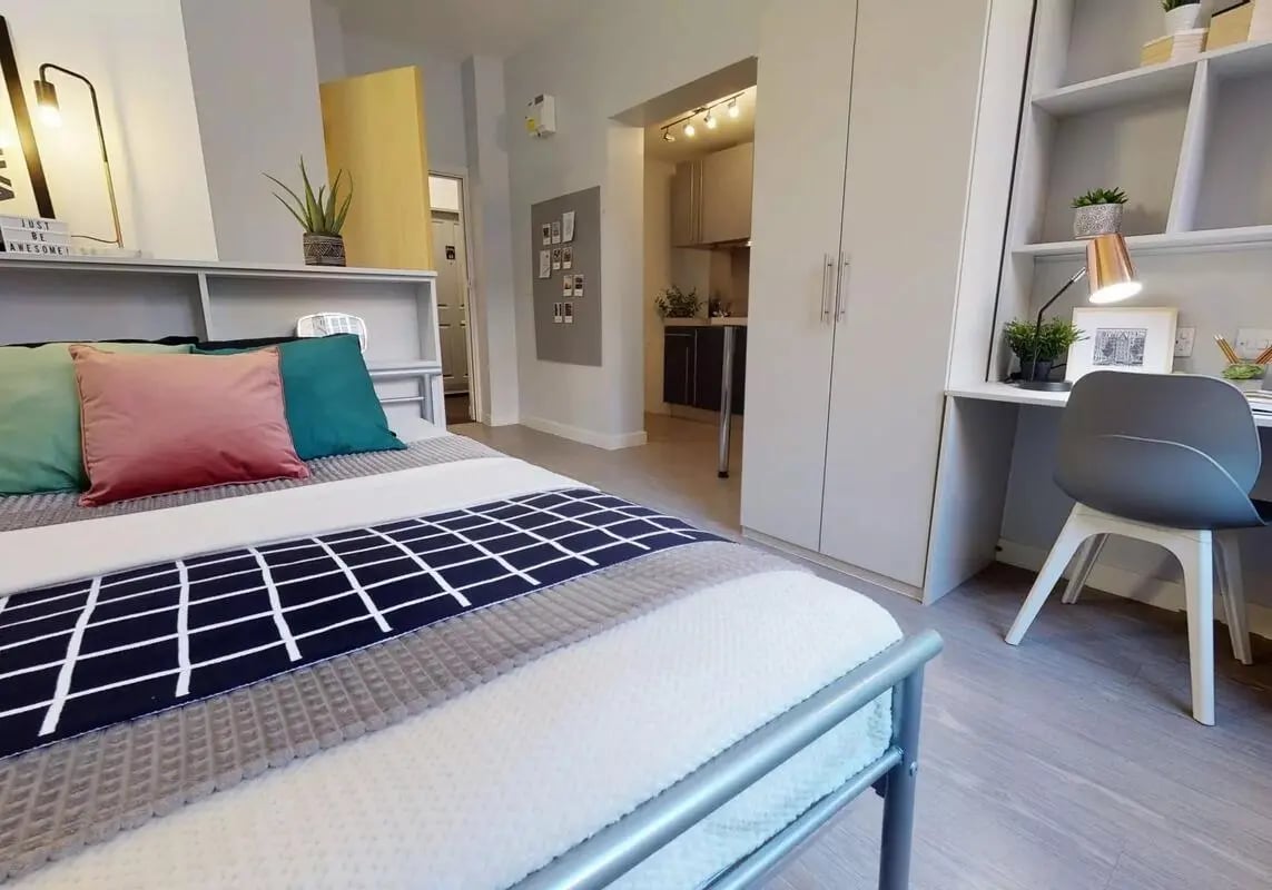 Bed pillows desk chair wardrobe kitchen area bedroom at iQ Studios 51 in Birmingham Student Accommodation